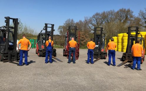 A picture containing workers on production site wearing T-Shirts with safety rules written on the backs.